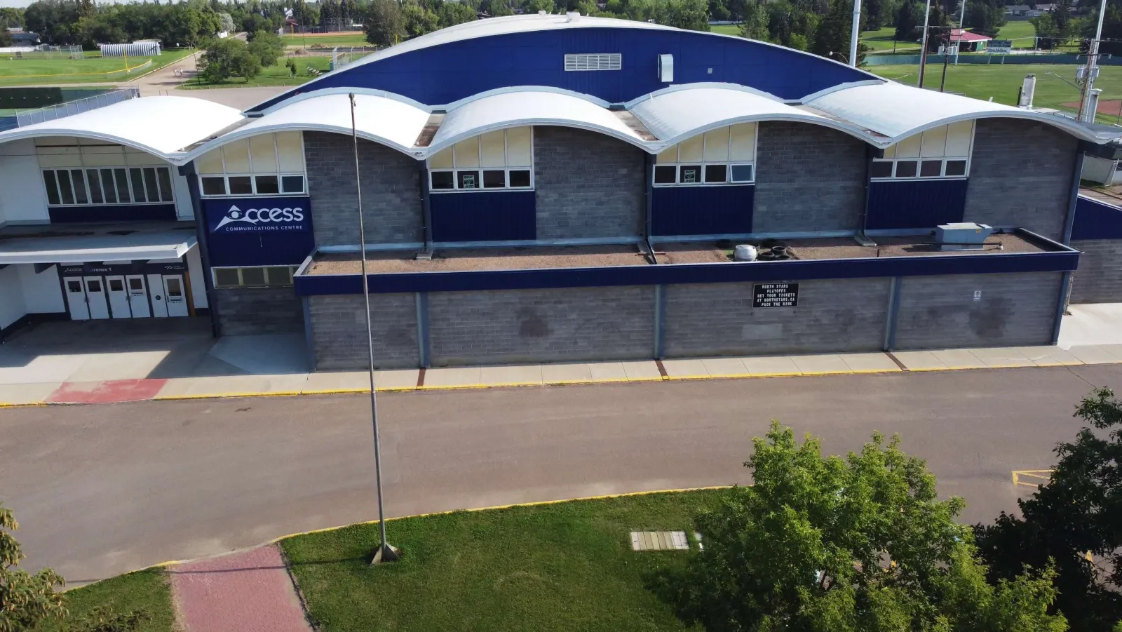 The Access Communications Centre from above: a long blue-and-white building with a row of curved roof sections and the Access sign over the entrance. — Access Communications Centre