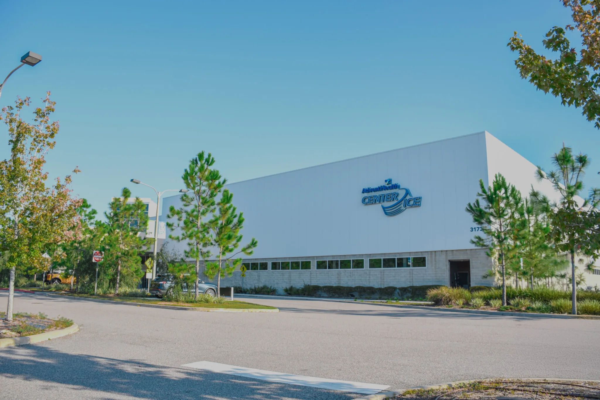 Tall white AdventHealth Center Ice building seen across the parking lot on a sunny day — AdventHealth Center Ice (Wesley Chapel)