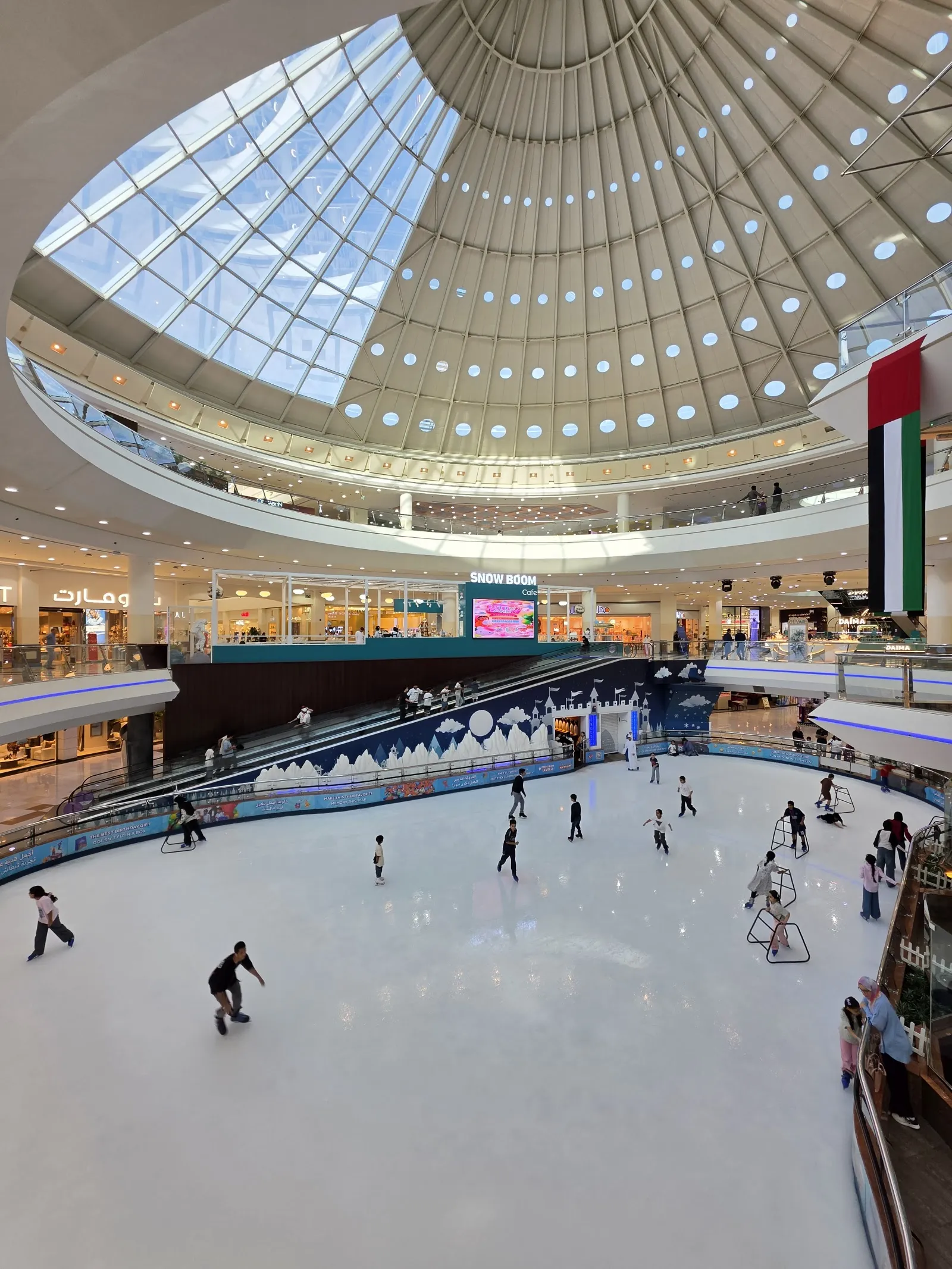 The rink on the ground floor of Al Ain Mall under the central dome, seen from the upper level with a few skaters — Al Ain Mall Ice Rink