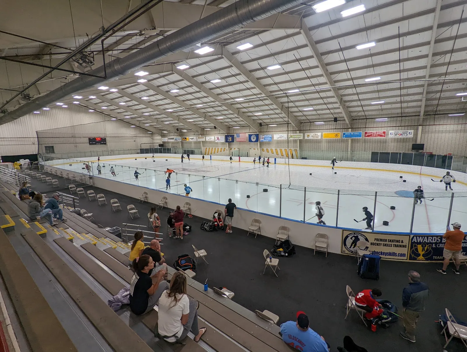 The main sheet at the Albany County Hockey Facility seen from the bleachers, with skaters on the ice — Albany County Hockey Facility