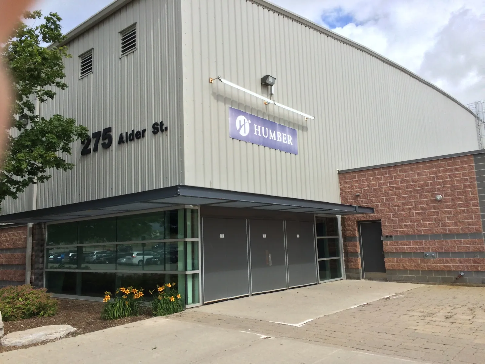 El ala de la arena con 275 Alder St. escrito en el revestimiento gris sobre una entrada de vidrio. — Alder Recreation Centre (Orangeville)
