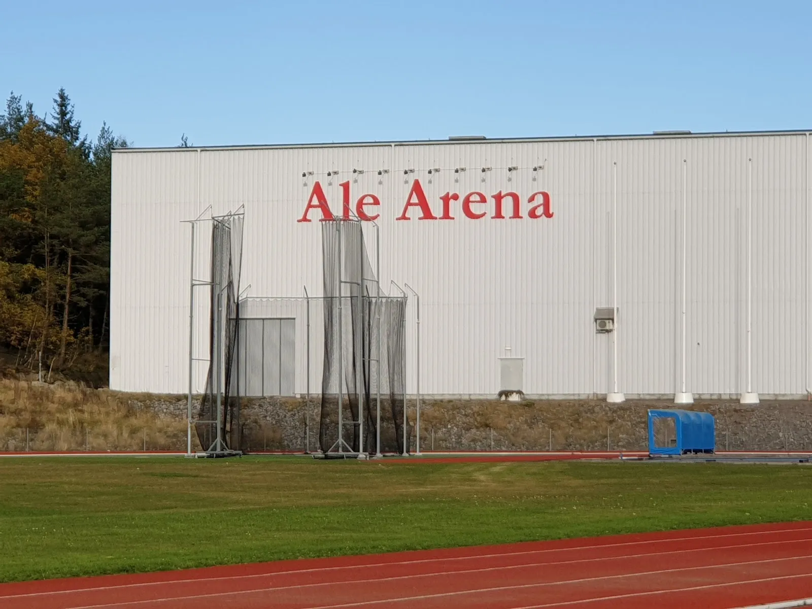 Den gråa hallen Ale Arena med sin röda namnskylt, sedd över löparbanan – Ale arena