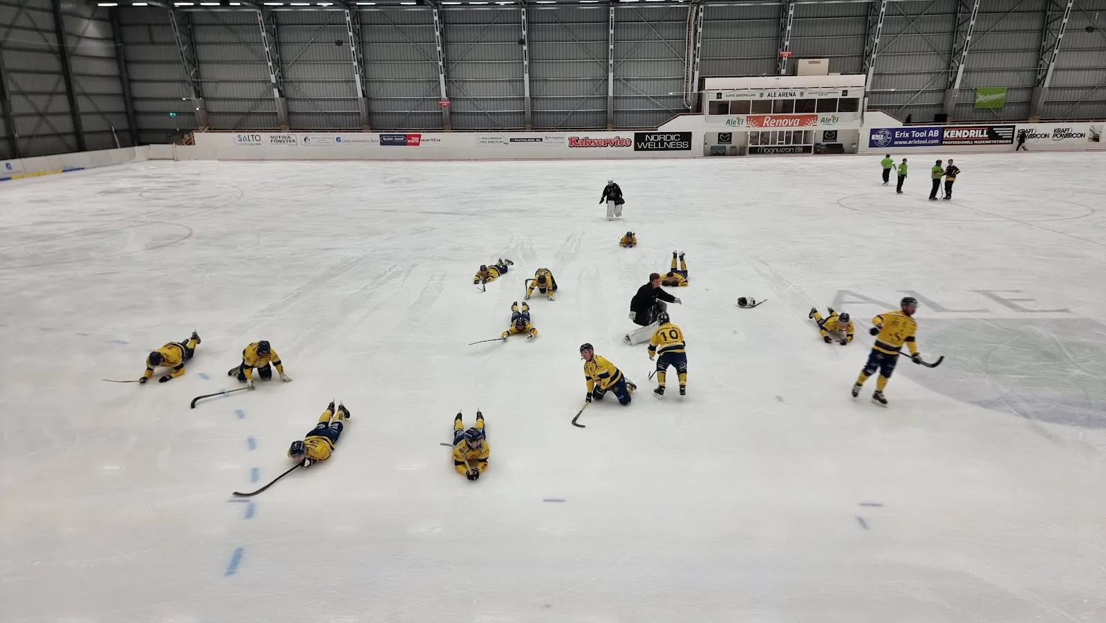 Isen i Ale Arena med ett bandylag i gula tröjor som värmer upp – Ale arena