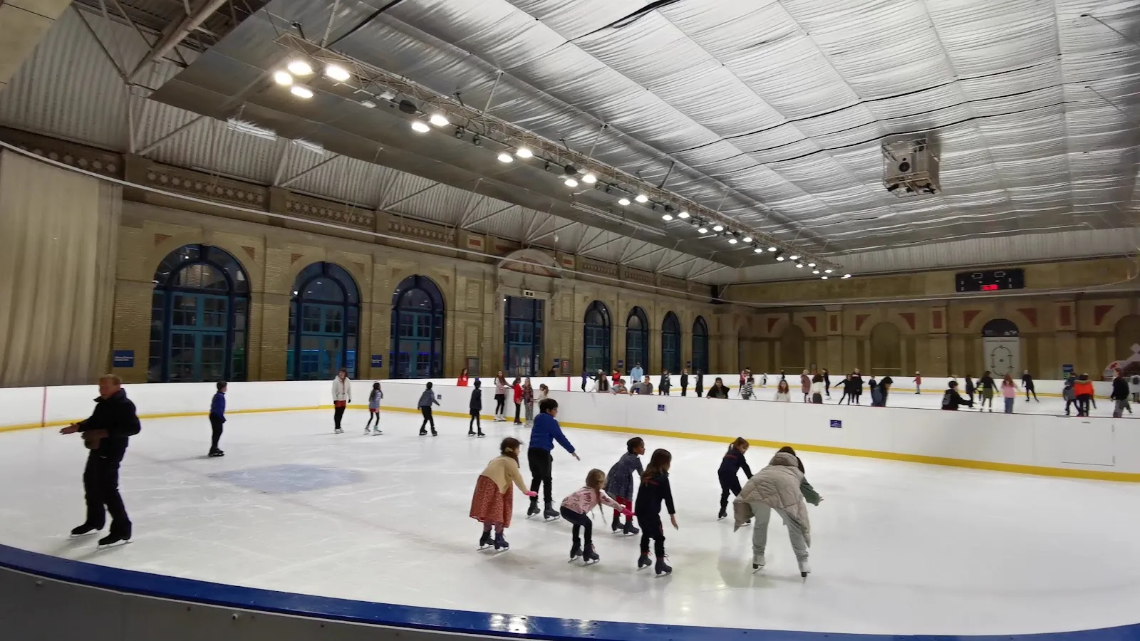 A public skating session on the ice, skaters at a distance beneath the Palace's hall roof — Alexandra Palace Ice Rink
