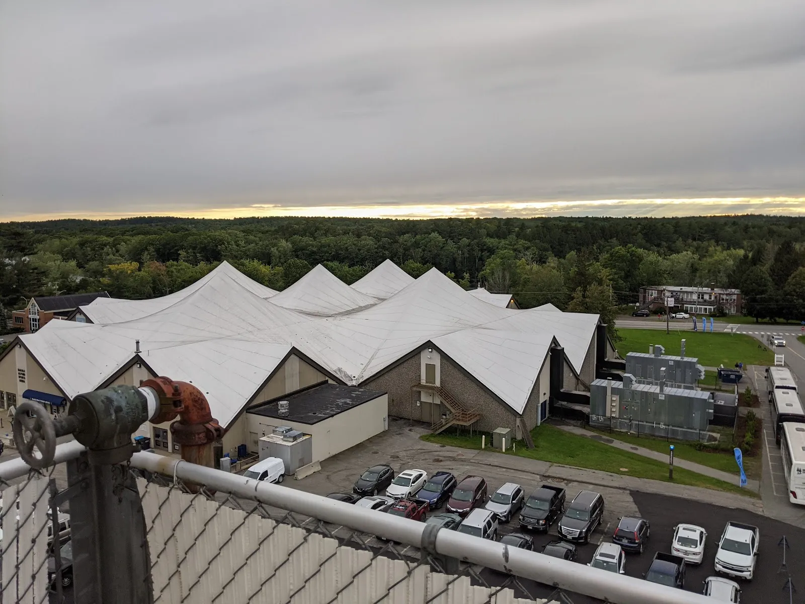 Aerial view of the peaked white roofs of Harold Alfond Sports Arena at the University of Maine, with the car park beside it — Alfond Arena