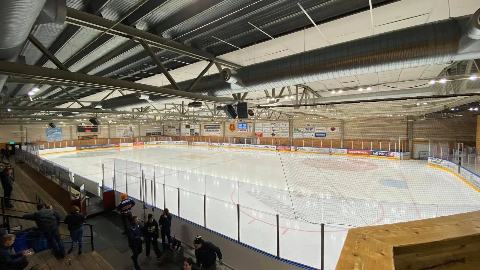 The ice of Virdavallen ishall seen from the stands, with the rink, boards and timber-clad walls — Alvesta ishall