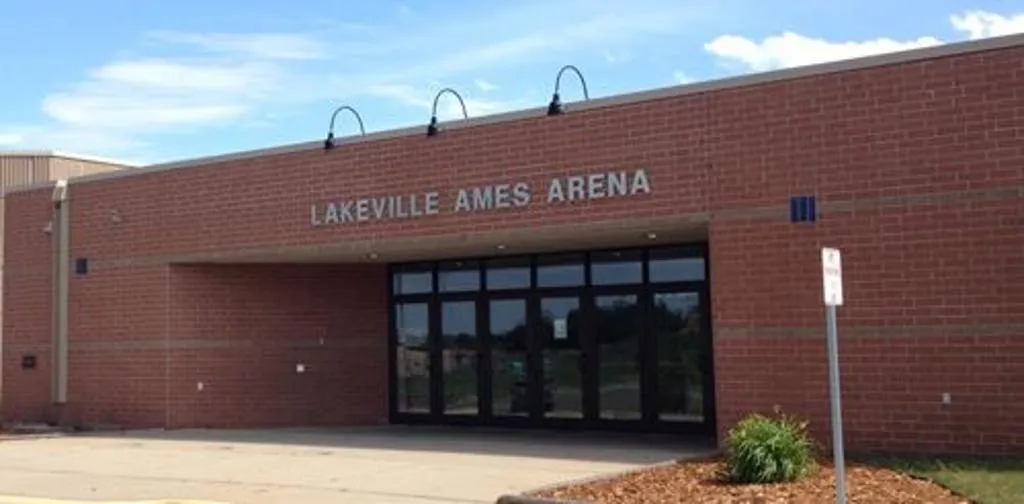 Entrada principal de un edificio de ladrillo con puertas de vidrio bajo un letrero que dice "LAKEVILLE AMES ARENA". — Lakeville Ames Arena (Lakeville Arenas)