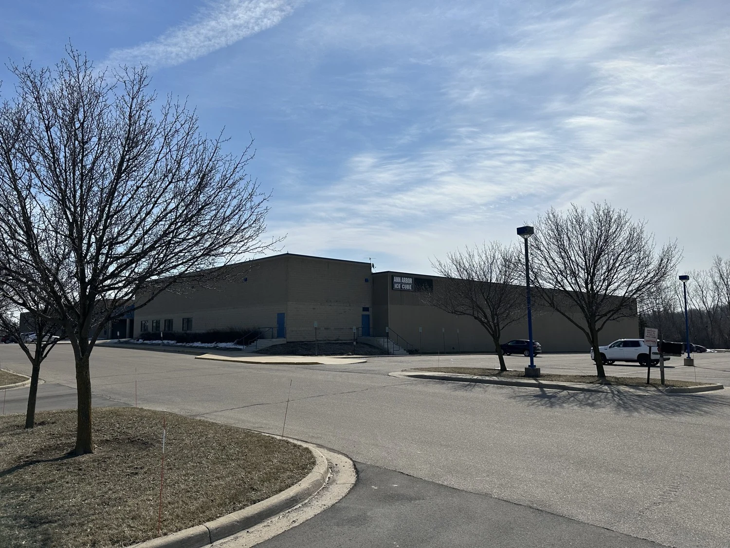 Ann Arbor Ice Cube's exterior and parking area, with bare trees in the foreground. — Ann Arbor Ice Cube