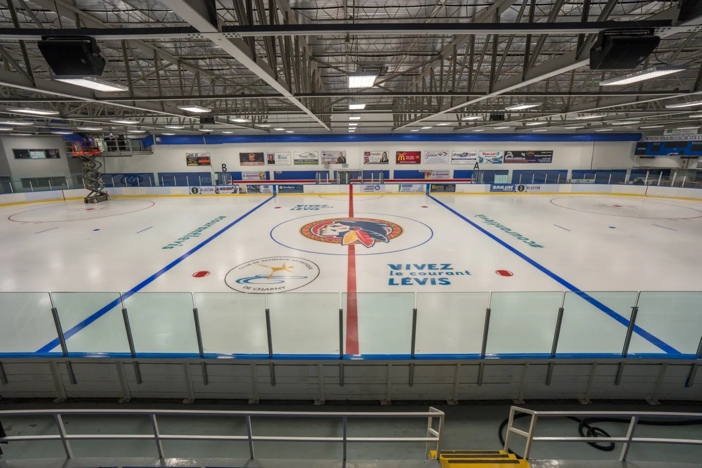 The arena ice seen from the stands, with the blue lines, centre-ice logo and boards. — Aquaréna Léo-Paul-Bédard