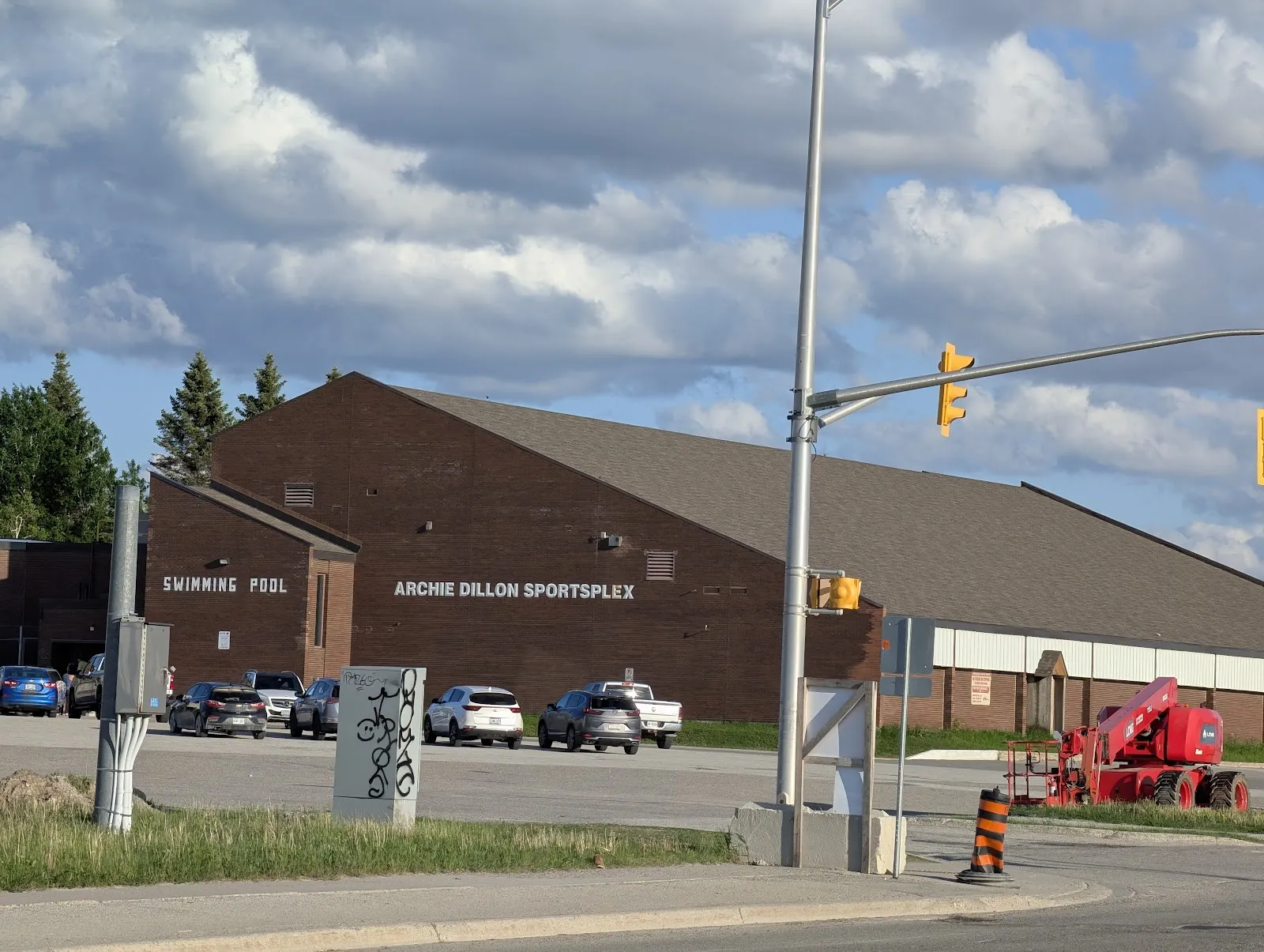 The brick Archie Dillon Sportsplex seen from the street corner, with the building sign, the swimming pool wing and the car park in front. — Archie Dillon Sportsplex