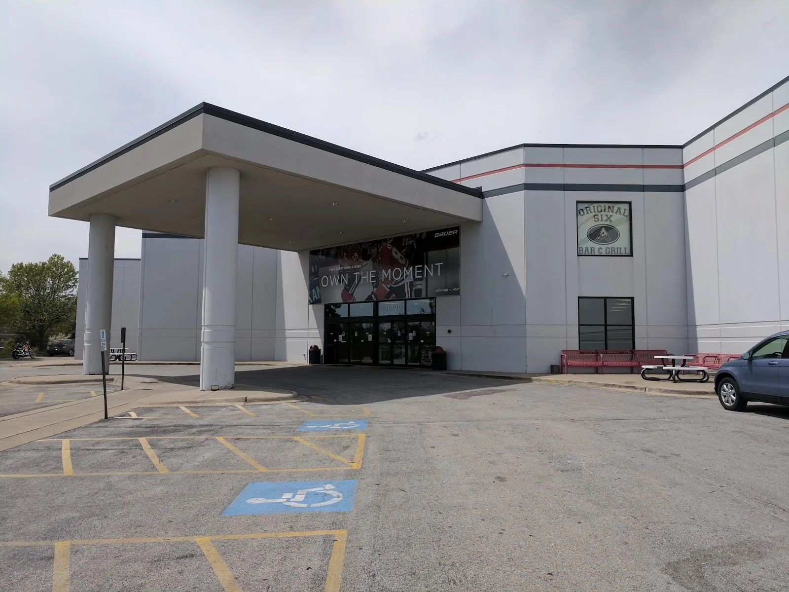 La entrada techada de Arctic Ice Arena en Orland Park, con sus puertas de vidrio y el letrero de Original Six Bar and Grill, vista desde el estacionamiento — Arctic Ice Arena (Orland Park)