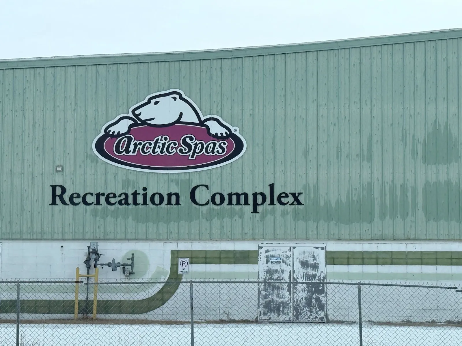 El muro de la arena revestido de verde con el letrero de Arctic Spas Recreation Complex y el logotipo del oso polar. — Arctic Spas Recreation Complex