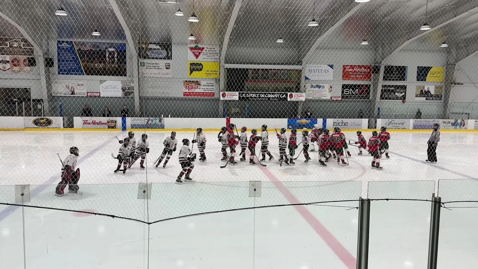 Young players on the ice at the Aréna Gilles-Cadieux, seen from the boards — Aréna Gilles-Cadieux
