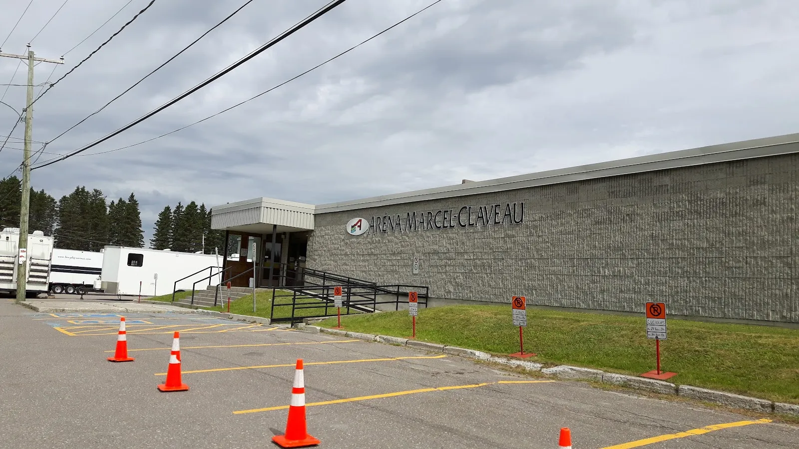The brick front of the Aréna Marcel-Claveau and its sign above the parking lot — Aréna Marcel-Claveau