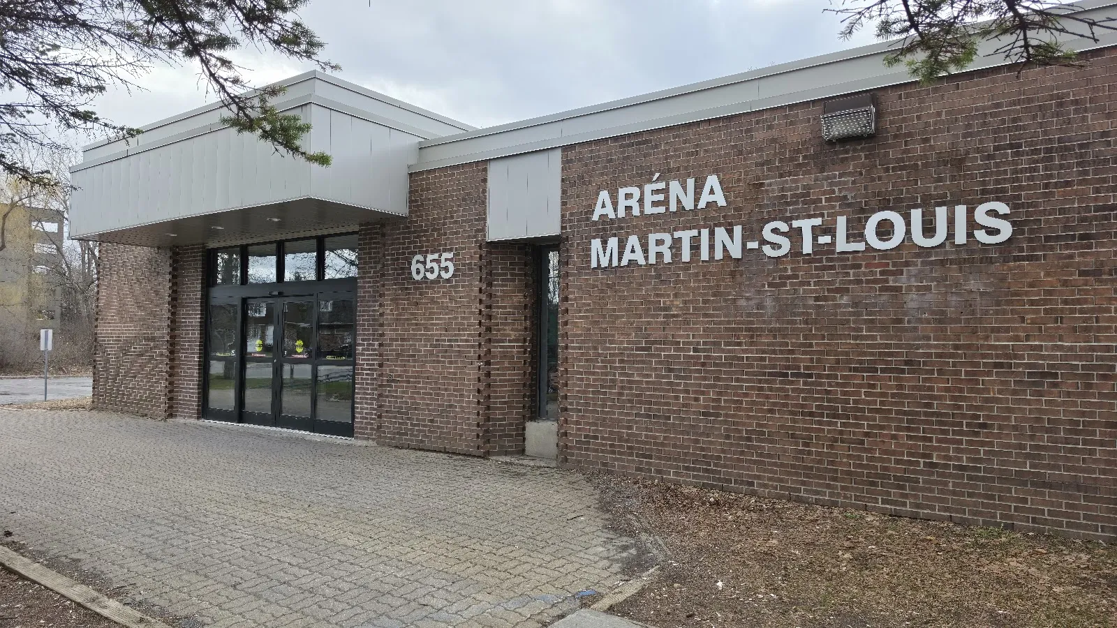 The brick entrance of Aréna Martin-St-Louis, with the civic number 655 and the name in metal letters beside glass doors under a flat canopy. — Aréna Martin-St-Louis (Laval)