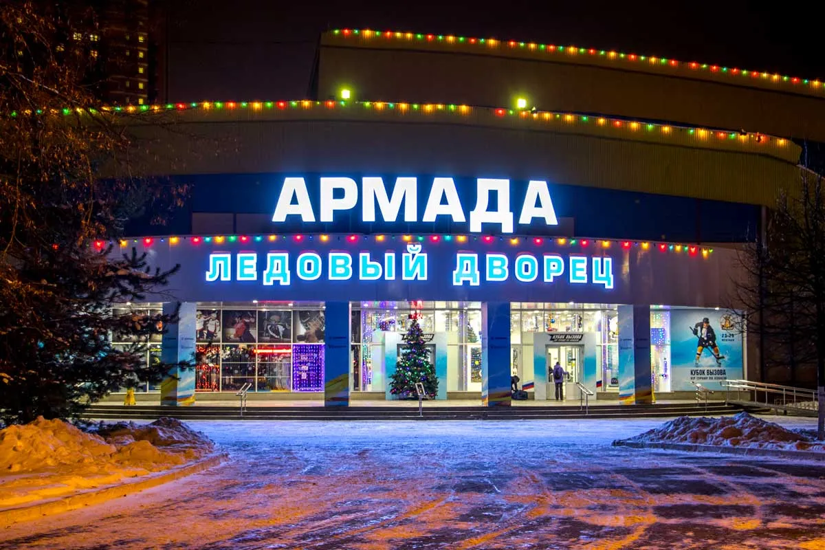 Фасад Ледового дворца «Армада» в Одинцово вечером: светящиеся вывески «АРМАДА» и «ЛЕДОВЫЙ ДВОРЕЦ» над стеклянным входом и праздничные огни вдоль крыши — Armada Ice Palace Odintsovo