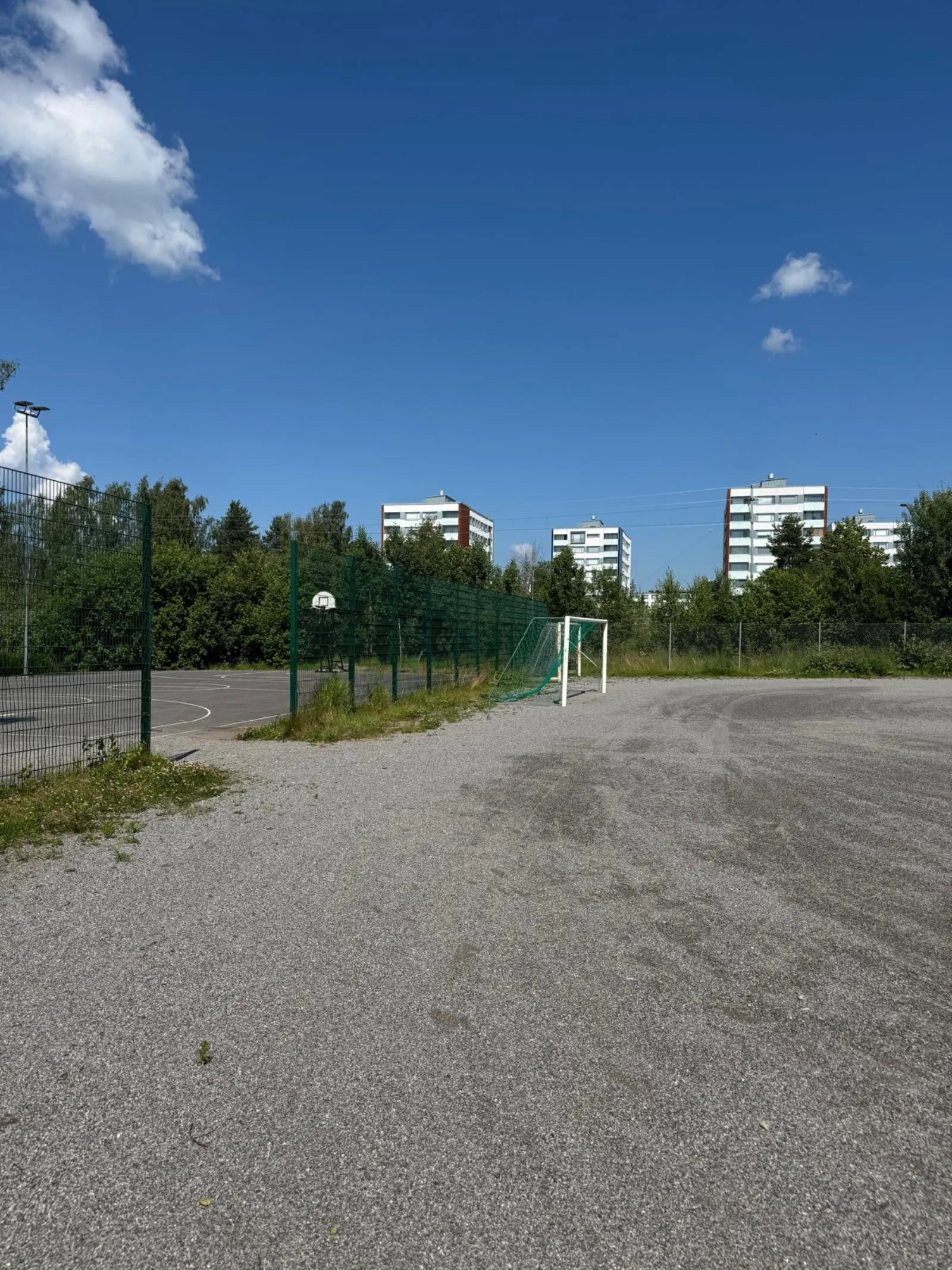 The Aunelan koulun field in summer, a ball field with a gravel (stone-dust) surface with goals; the City of Turku freezes its fields into skating fields in winter. — Aunelan koulun luistelukenttä
