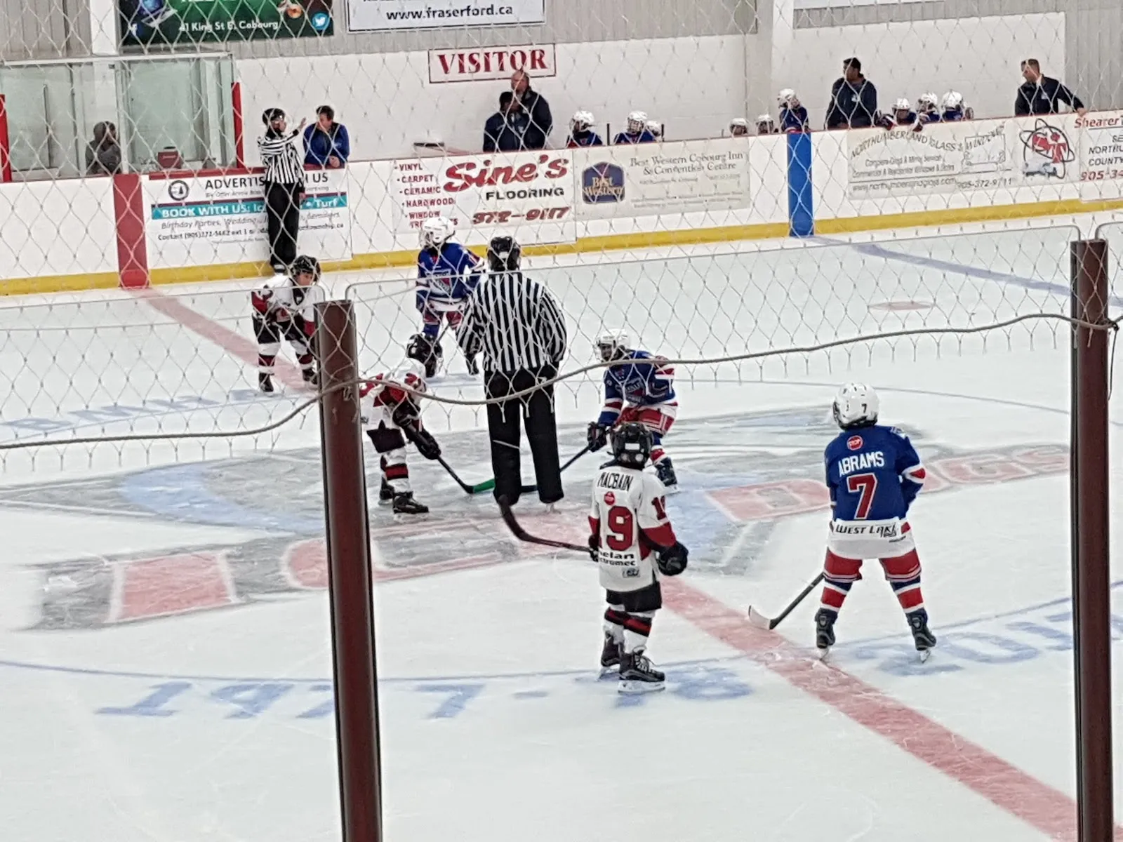 Players meeting at a faceoff on the Baltimore arena ice, with advertising boards and the stands behind. — Baltimore Recreation Centre