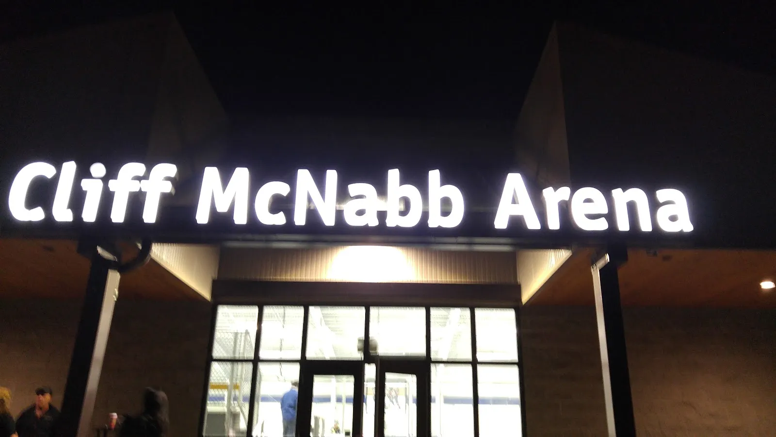 The glass entrance of the Cliff McNabb Arena at Beban Park at night, its name in large lit letters above the doors and the lobby glowing inside. — Frank Crane Arena and Cliff McNabb Arena (Beban Park)