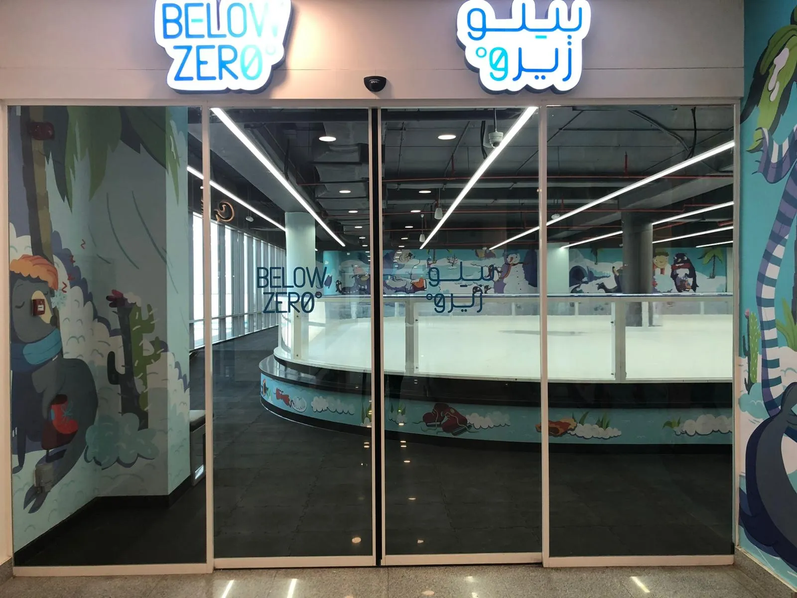 أبواب المدخل الزجاجية لـ«بيلو زيرو» في الجهراء مول، والحلبة ظاهرة من الداخل — Below Zero (Jahra Mall)