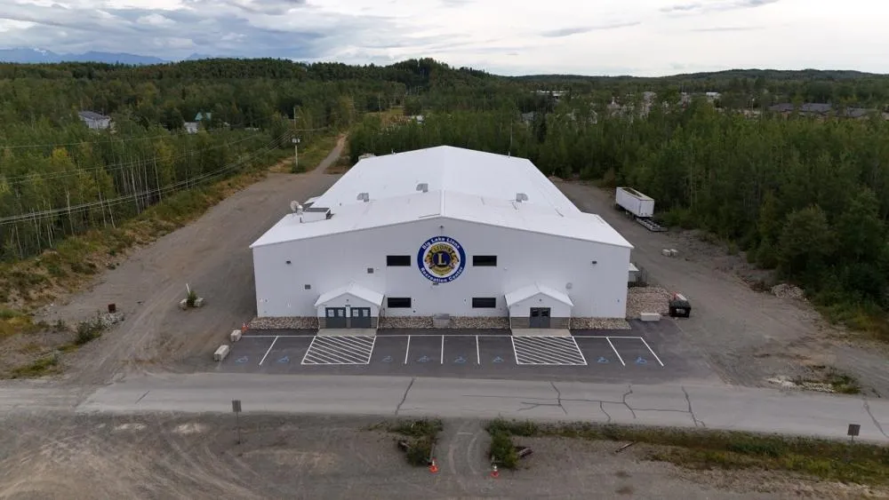 Vista aérea del Big Lake Lions Recreation Center, un gran edificio blanco con estacionamiento delante y árboles alrededor. — Big Lake Lions Recreation Center