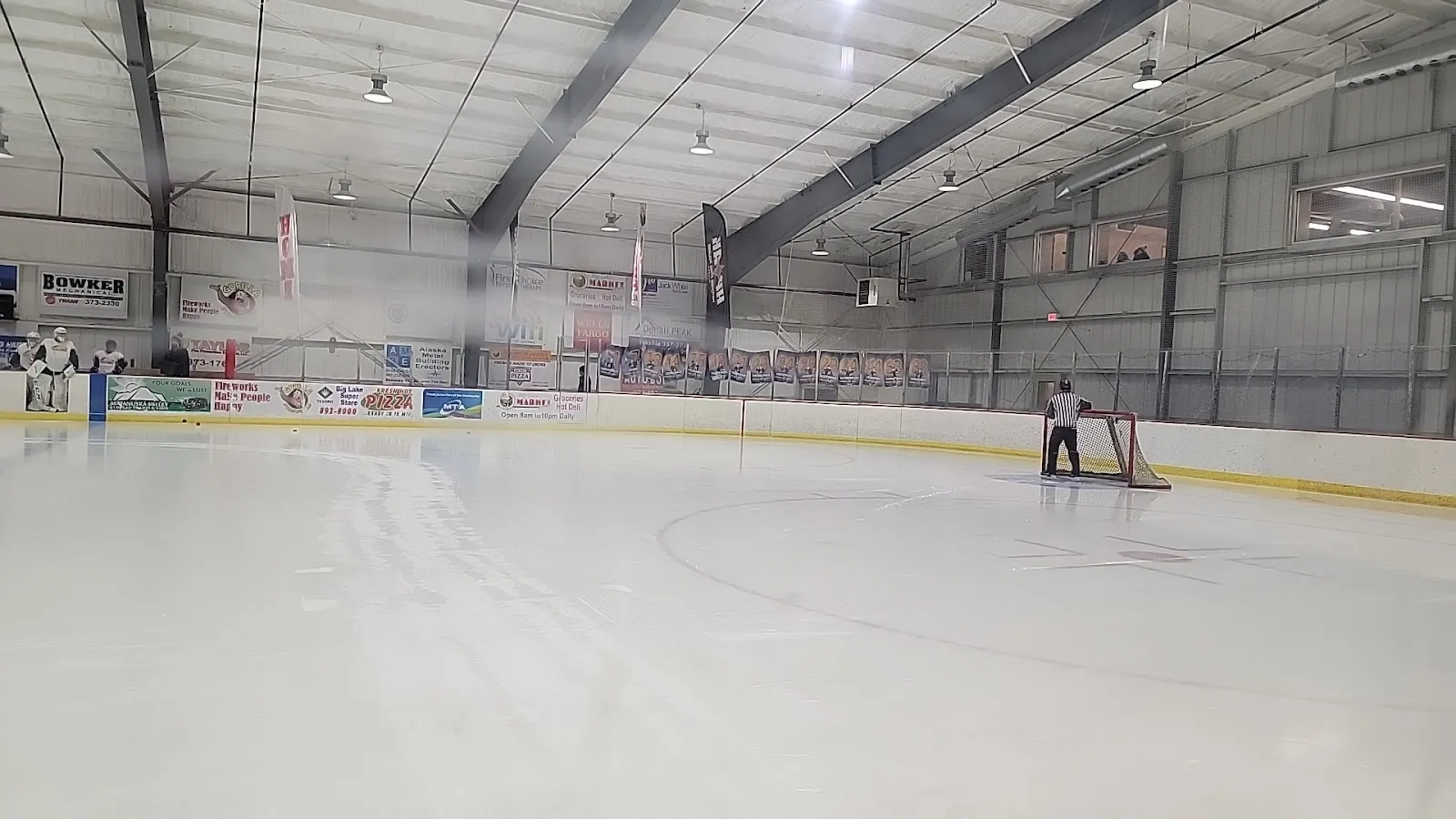 The empty ice under the steel-framed roof of the Big Lake Lions arena with the boards in the distance. — Big Lake Lions Recreation Center