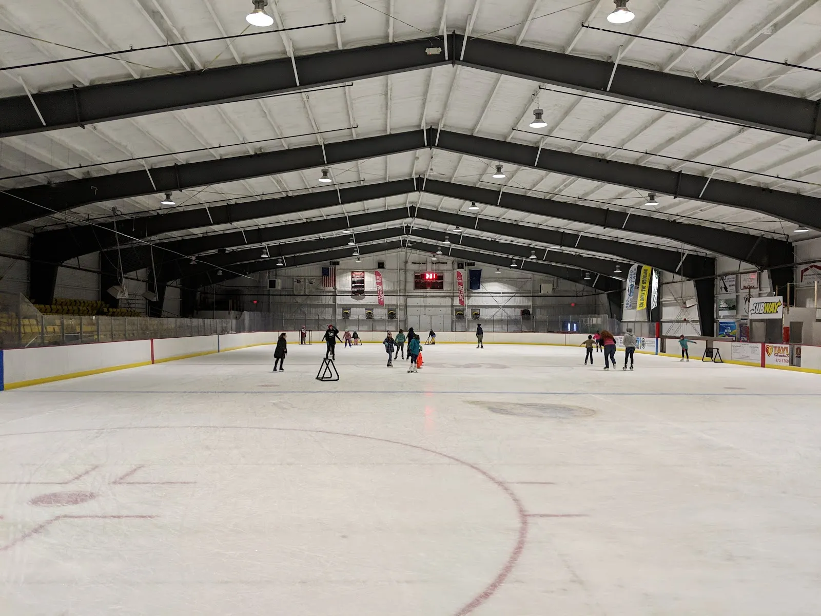 Skaters far down the Big Lake Lions arena ice beneath the dark roof trusses. — Big Lake Lions Recreation Center
