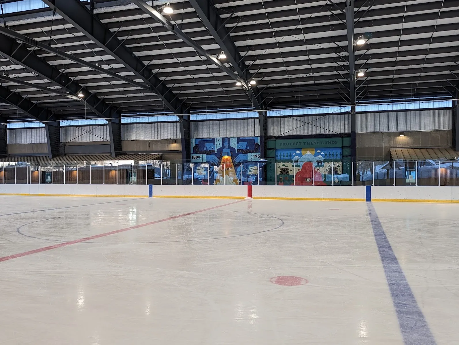 The empty ice sheet under the arena's steel roof — Big Mine Ice Arena