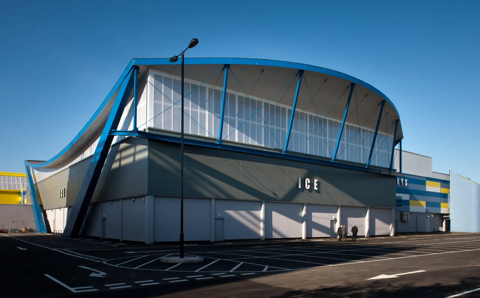 The ice arena wing of Billingham Forum from its car park: a curved, glazed roof over a grey block wall with ICE in large letters. — Billingham Forum Ice Arena