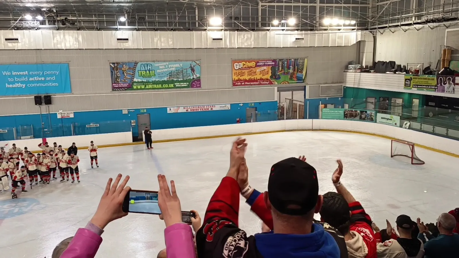 Wide view across the ice sheet at Billingham Forum during a club event, with teams lined up on the ice, the rink boards, sponsor banners and the roof behind. — Billingham Forum Ice Arena