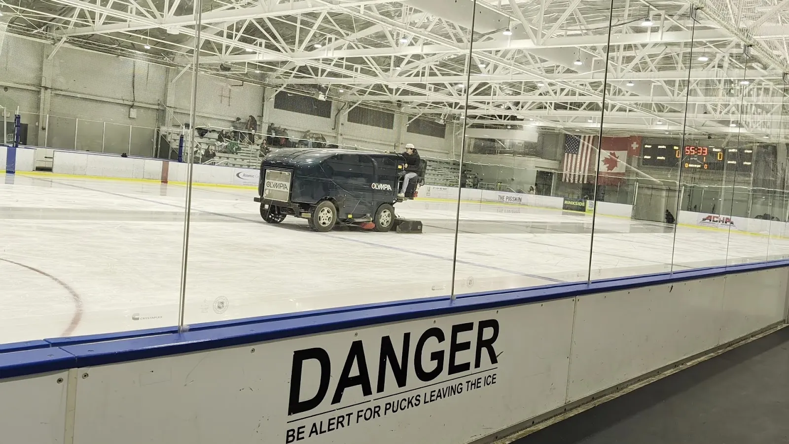 The ice surface at Bird Ice Arena with the resurfacer at work, seen through the boards glass. — Bird Ice Arena