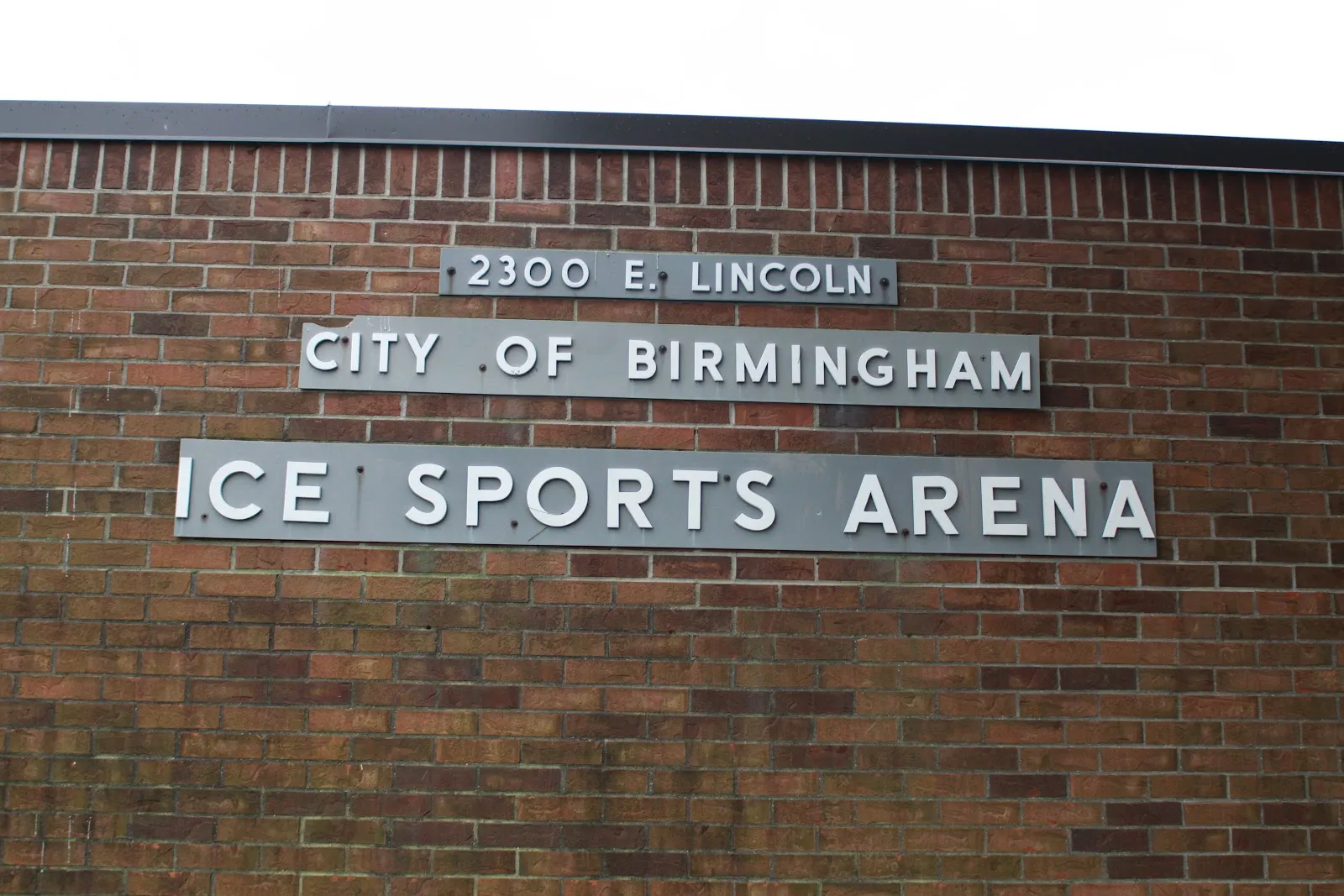 A brick wall sign reading "2300 E. Lincoln / City of Birmingham / Ice Sports Arena", mounted on the building's exterior brick facade. — Birmingham Ice Sports Arena