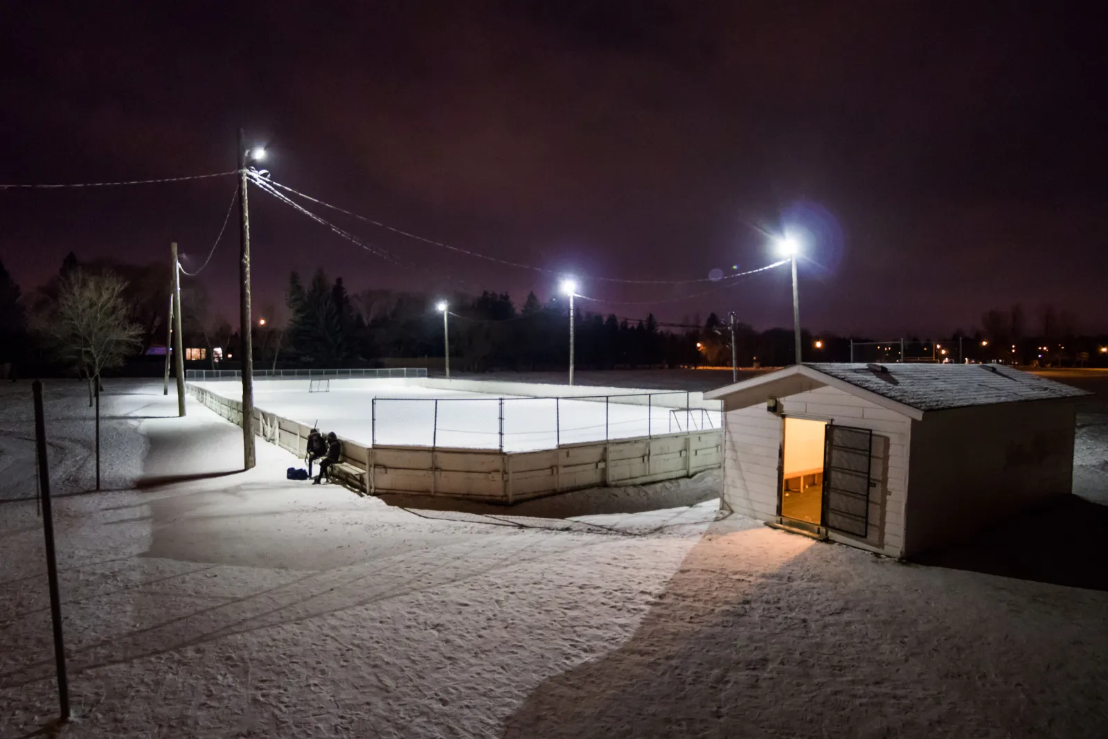 La pista comunitaria de Wildwood de noche con la caseta de calentamiento (página de la pista de la Wildwood Community Association) — Bishop Pocock School Outdoor Rink (Wildwood)