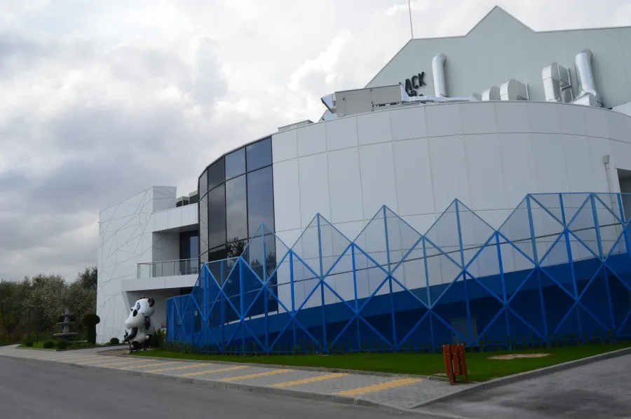 The Black Sea Ice Arena building in Kranevo: a white faceted two-storey block with a curved glazed front, a blue zig-zag lower wall and the arena name on the roofline. — Black Sea Ice Arena