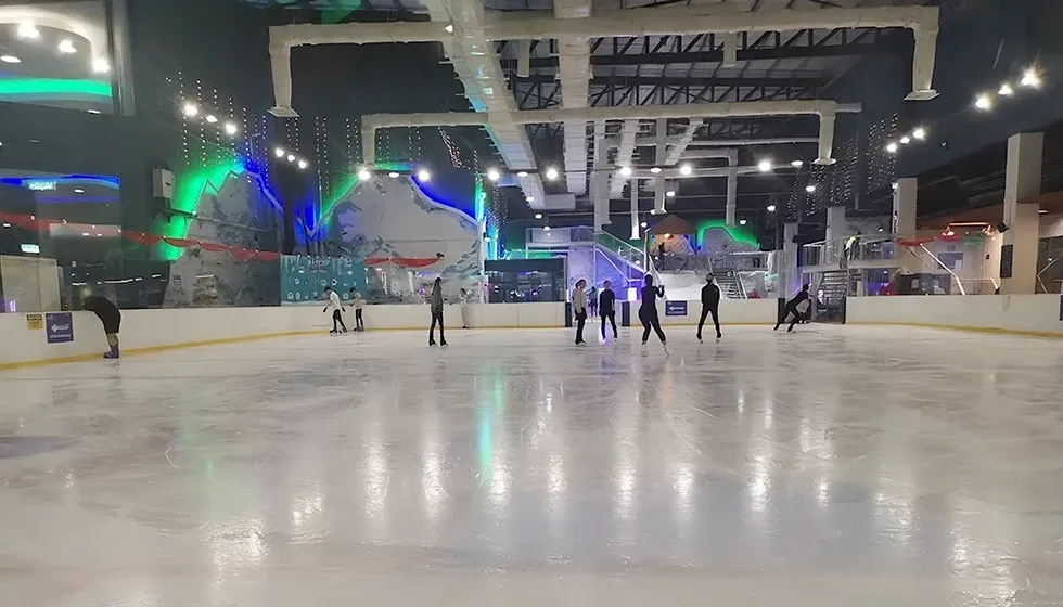 The ten-thousand-square-foot sheet at Pavilion Bukit Jalil, lit in blue and green, with skaters at the far end. — Blue Ice Snow Park Pavilion Bukit Jalil