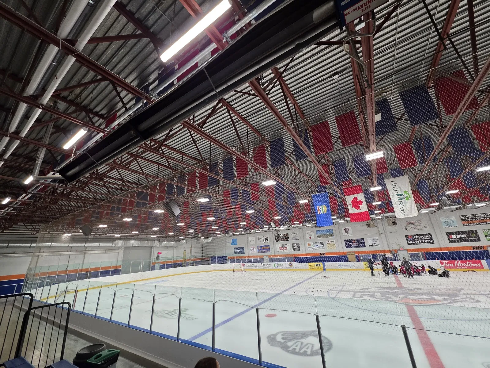 La arena grande de Bob Snodgrass Recreation Complex, con mantas rojas y azules y banderas que cuelgan de las armaduras del techo sobre el hielo. — Bob Snodgrass Recreation Complex