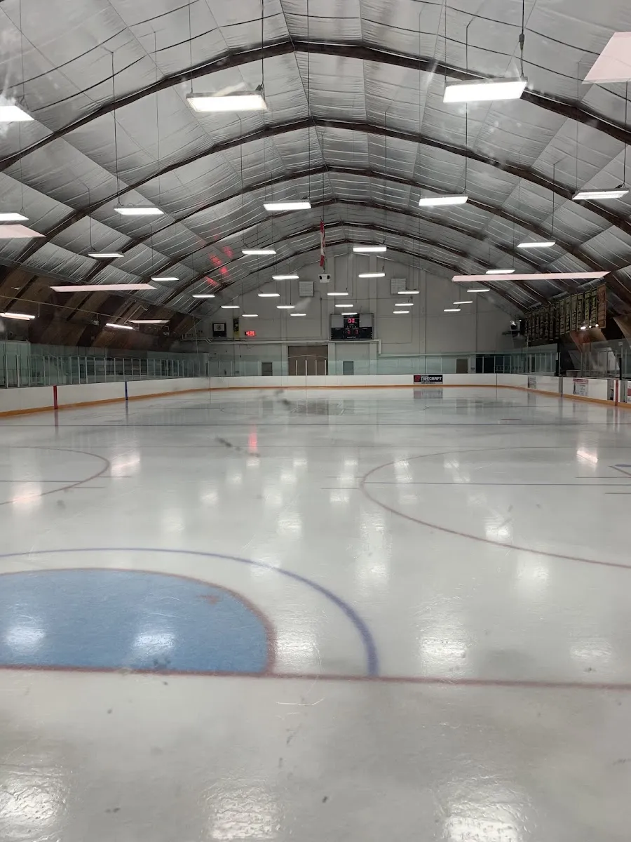 La pista de hielo vacía bajo el techo arqueado, vista desde las vallas de un extremo hacia el otro. — Bond Lake Arena (Richmond Hill)