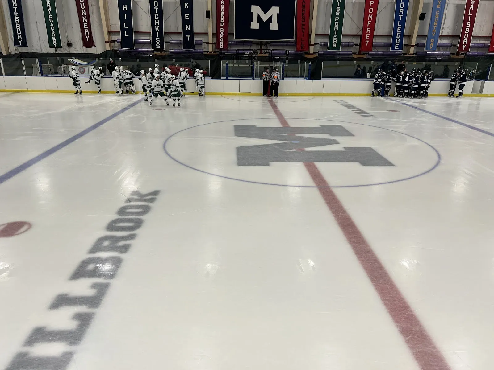 The empty ice at Bontecou Rink with a large M at centre ice, a red line and the team banners above the boards. — Bontecou Rink at Millbrook School