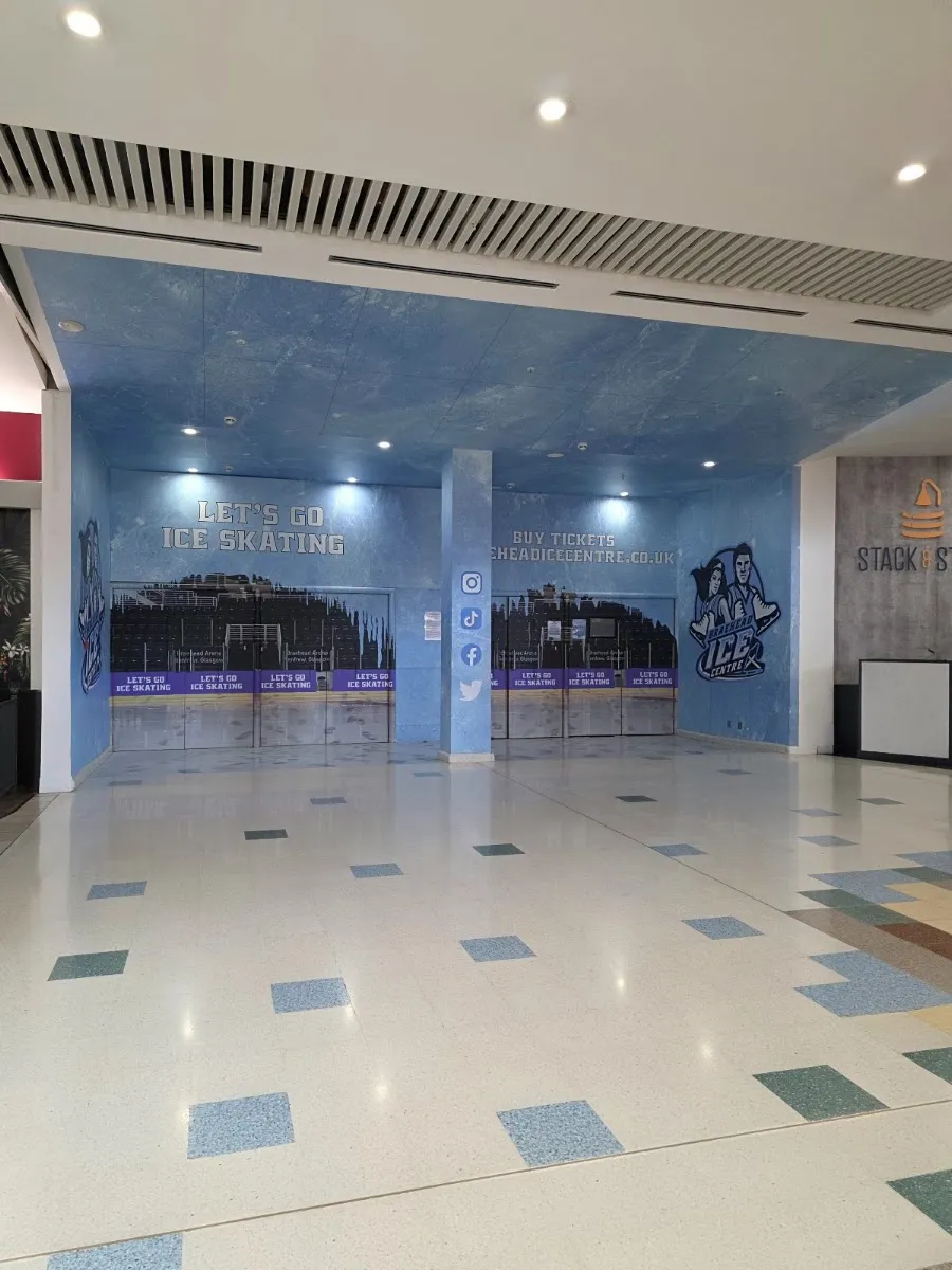 The ticket-office frontage of Braehead Ice Centre inside the Braehead shopping centre concourse: a blue marble-effect wall lettered 'Let's go ice skating - buy tickets' with the centre's logo and a row of ticket hatches. The rink has no street-facing front of its own. — Braehead Ice Centre
