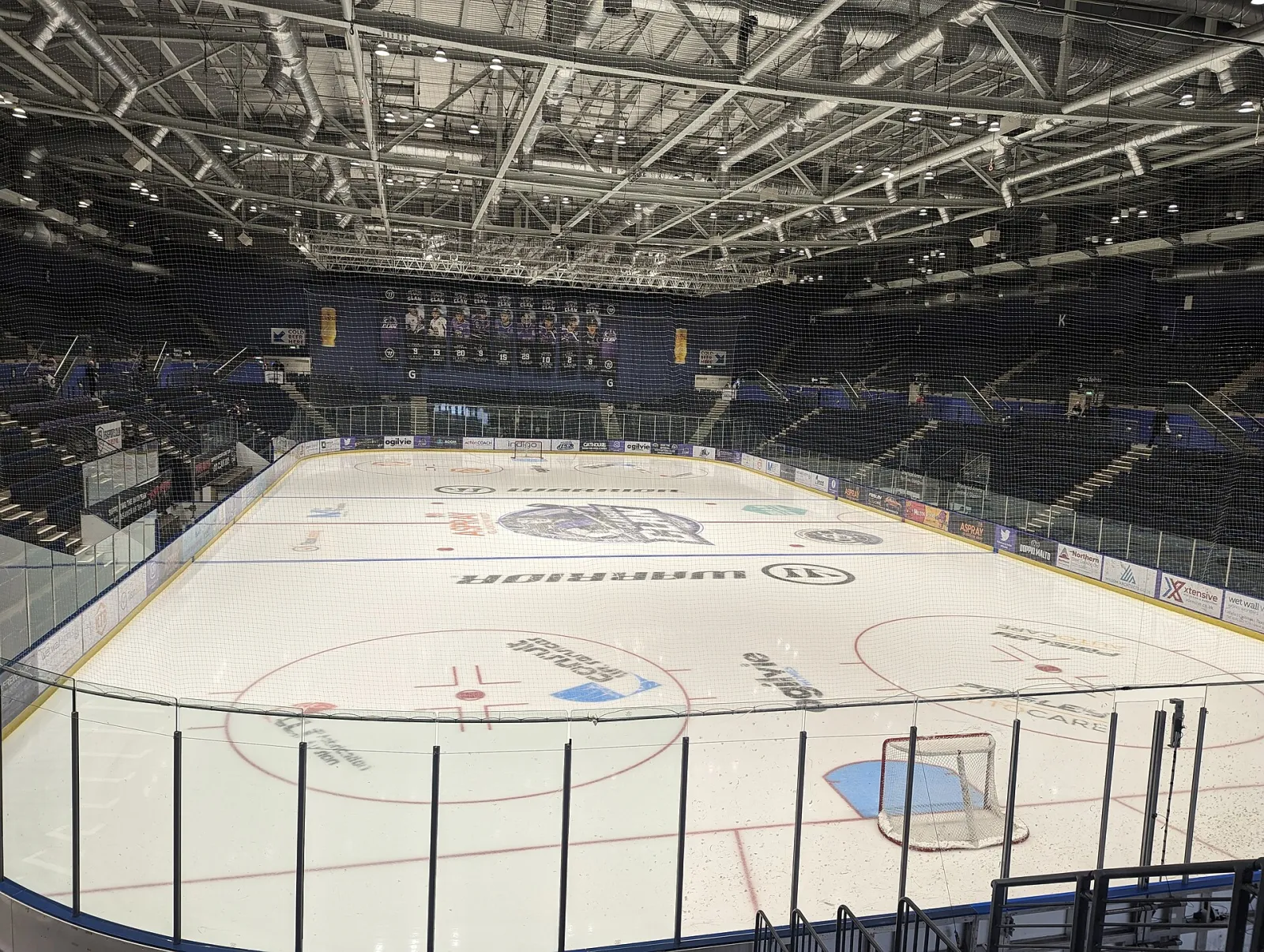 The empty ice from the stands before a Glasgow Clan game, with the seating bowl and steel roof trusses above. — Braehead Ice Centre