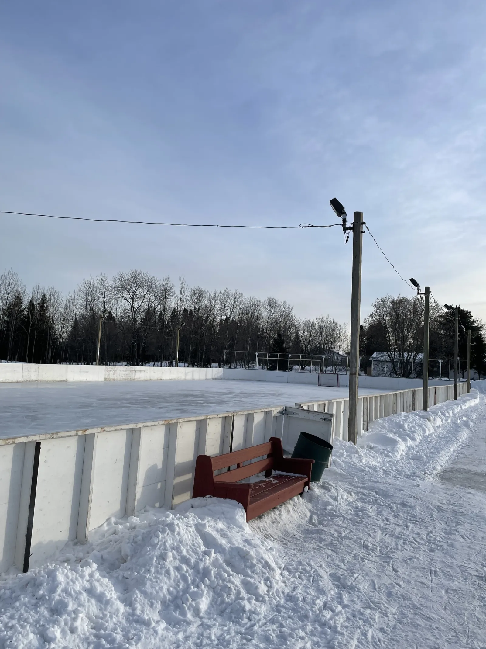 Vallas, una banca y un bote de basura junto al hielo en Brent Park — Brent Park Outdoor Rinks