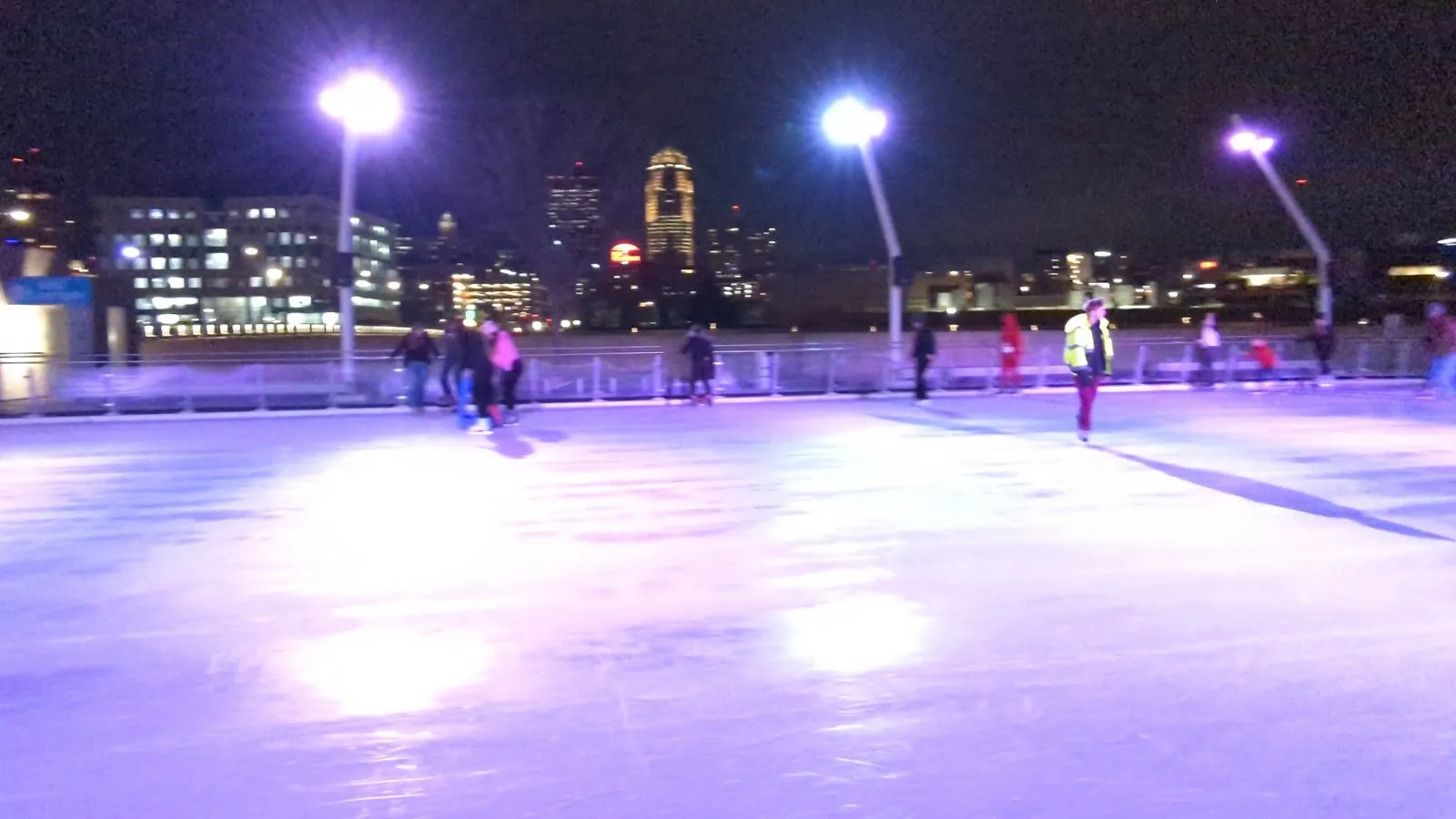 The lit Brenton Skating Plaza ice at night with the downtown Des Moines skyline behind (Google Maps listing photo) — Brenton Skating Plaza