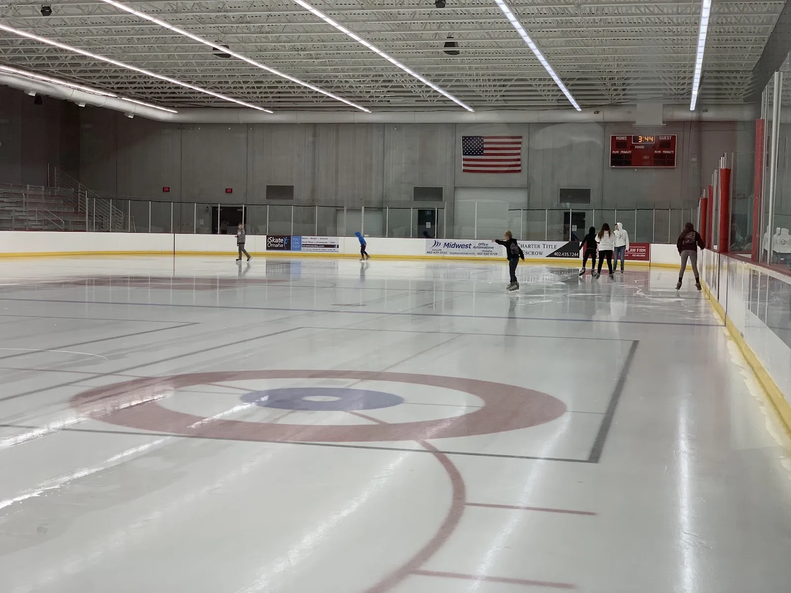 Public skating at the John Breslow Ice Hockey Center, a few skaters spread across the ice under a grey concrete hall — John Breslow Ice Hockey Center