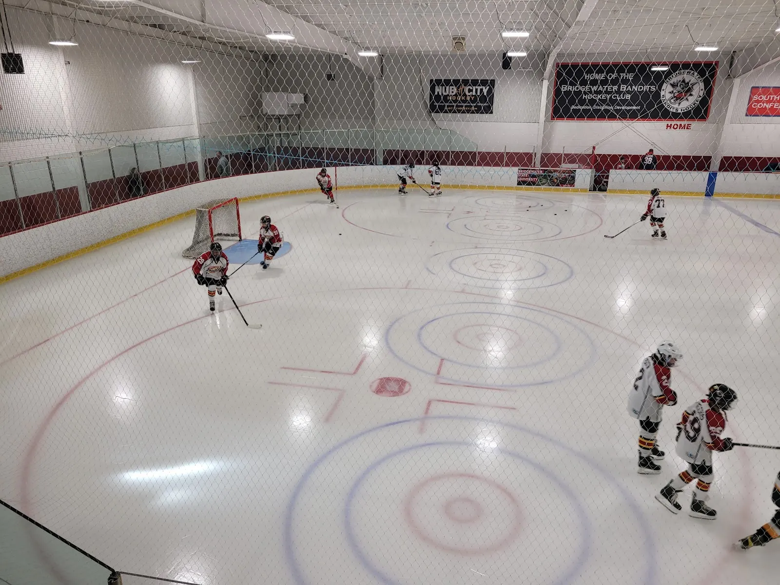 Wide view of the ice sheet at Bridgewater Ice Arena with skaters at a distance and the curling-style centre rings — Bridgewater Ice Arena