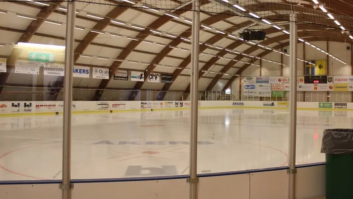 The ice surface of the Bruksvallens ishall in Åkers Styckebruk, seen from behind the boards under the wooden roof beams. — Bruksvallens ishall