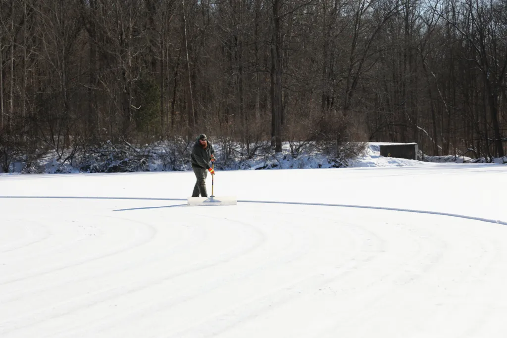 Brushwood Lake at Furnace Run in Richfield with snow cleared from the ice and a person clearing more snow in the distance. — Brushwood Lake Ice Skating at Furnace Run Metro Park