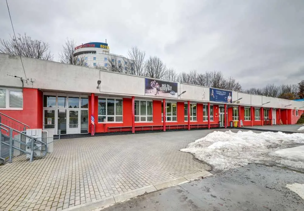 The red-and-white building beside the ice with changing rooms, skate rental and a snack bar — Bruslení za Lužánkami