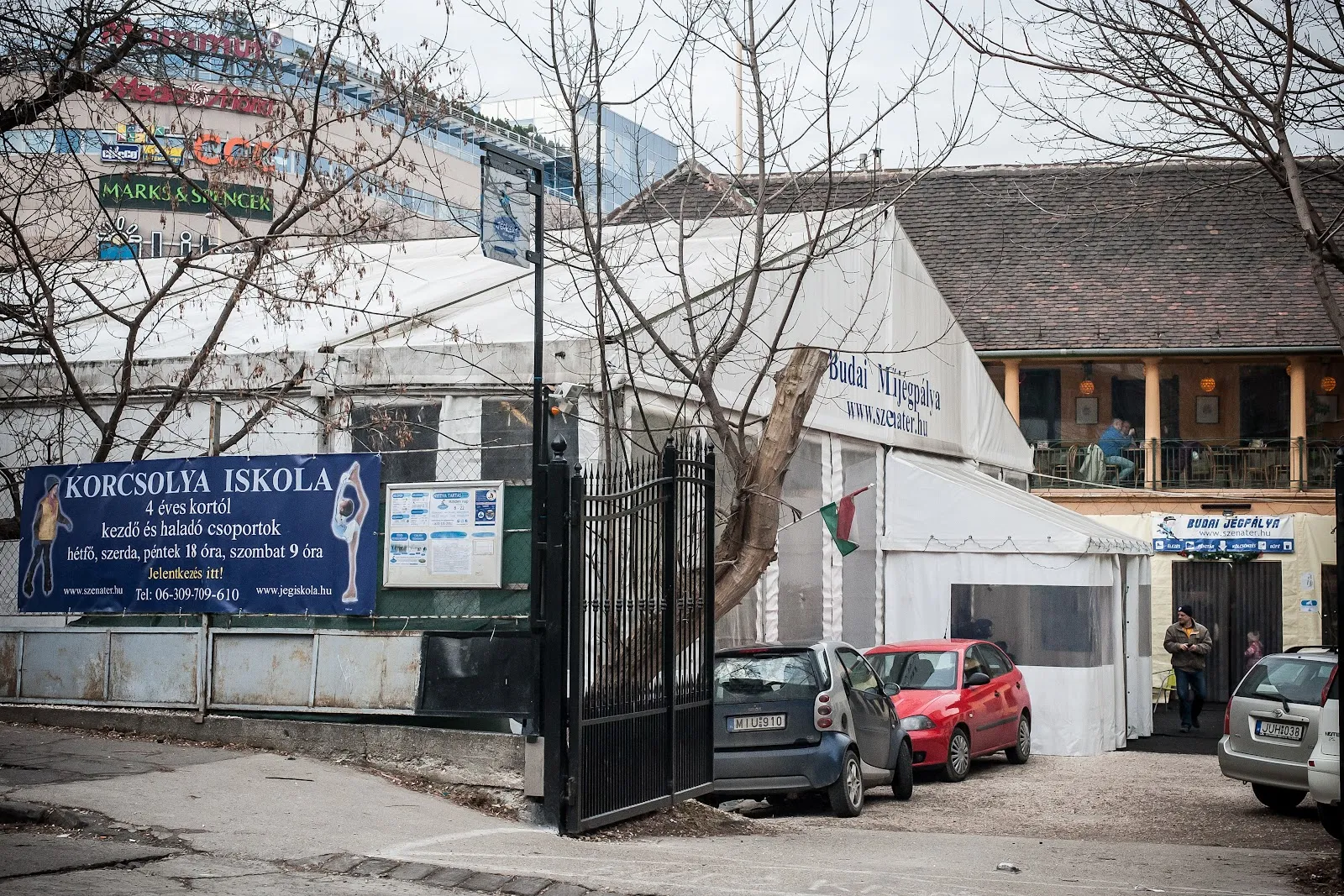 The street entrance of the Budai Jégpálya (Jégkert) off Bakfark Bálint utca, with the white rink tent behind the gate — Budai Jégpálya (Jégkert)