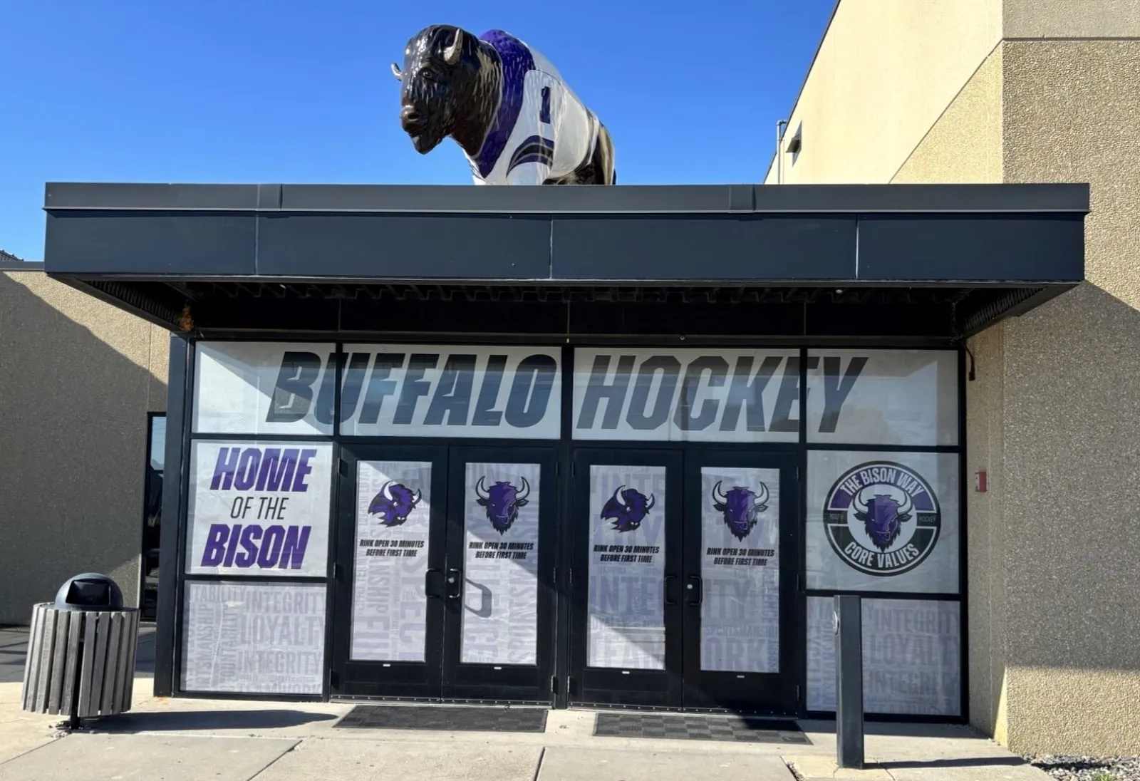 The Civic Center entrance with BUFFALO HOCKEY and 'Home of the Bison' on the glass doors and a bison statue in a hockey jersey on the canopy. — Buffalo Civic Center