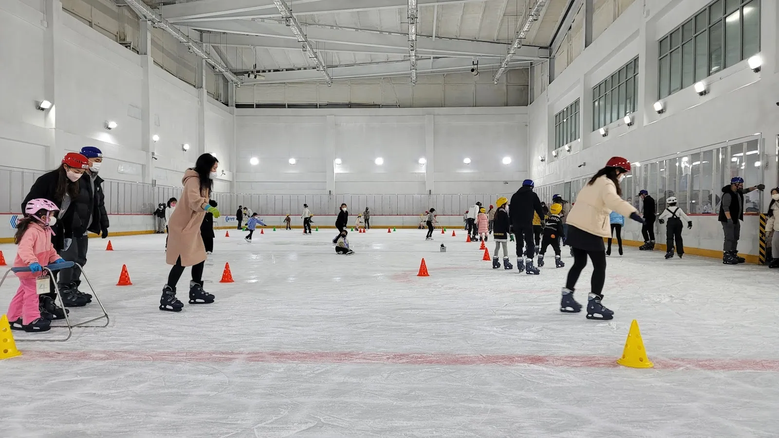 Children skating around training cones on the ice of the Byeollae ice rink in Namyangju, seen from the boards across the hall. — Byeollae Ice Rink (Namyangju)